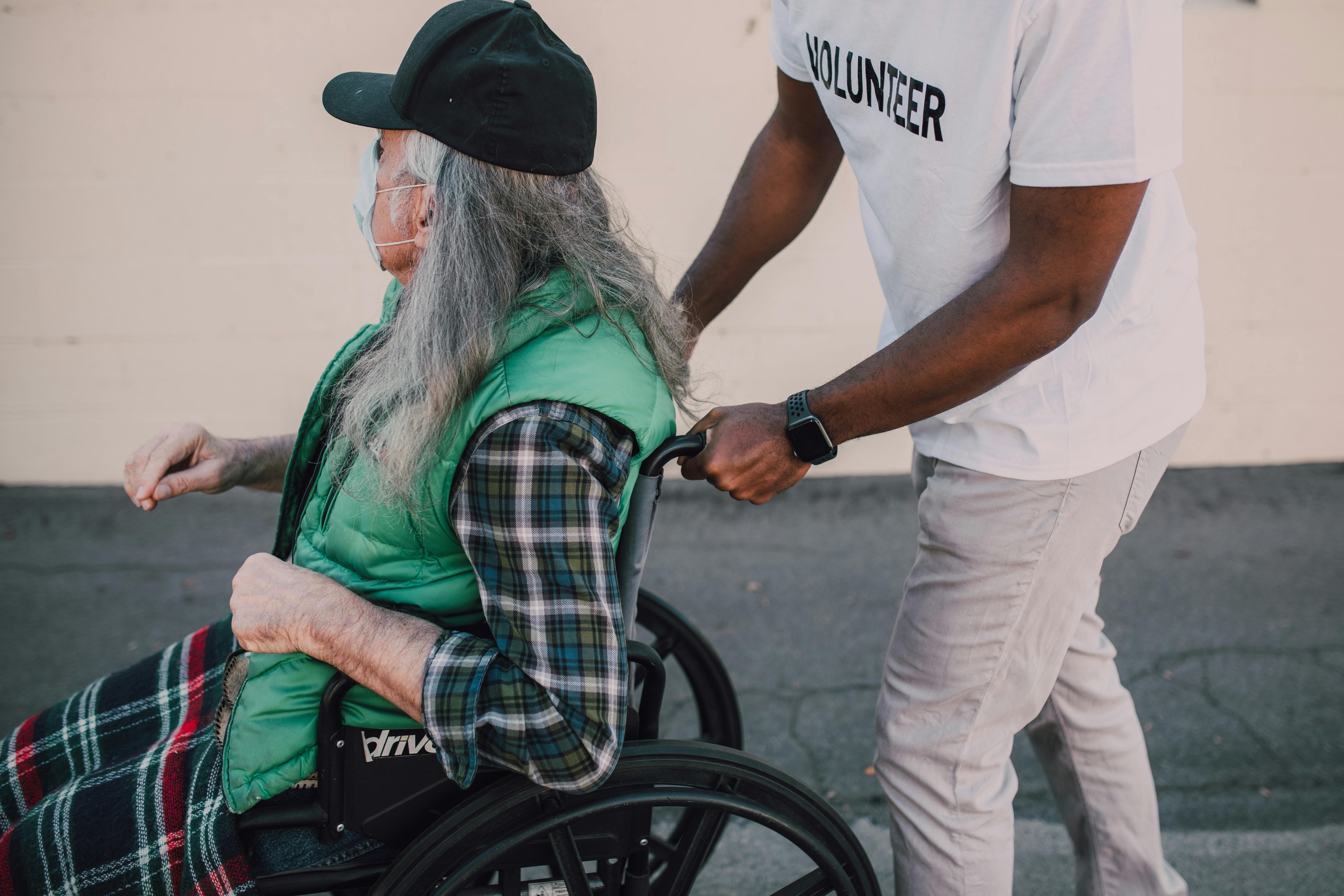 Volunteer assisting an elderly person in a wheelchair